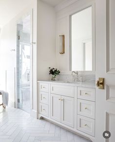 a bathroom with white cabinets and marble counter tops