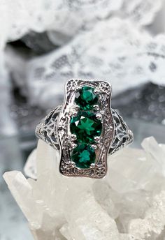 "Natural Green Emerald Ring 3Stone Rectangle Design#60 Custom Made This is a lovely late Victorian era reproduction ring in solid sterling silver. The gorgeous filigree ring is set with 3 round-cut Natural Green Emerald (color/heat treated) gemstones. The 2 smaller gems are 4.5mm in diameter, and the center one is 6mm in diameter. This filigree setting is a casting from an actual Antique ring; notice the amazing etched band... The ring sits 3/4th\" (19mm) NS on the finger. The quality of the sil Silver Emerald Ring With Three Stones For Promise, Silver Three Stone Emerald Ring For Promise, Silver Three-stone Emerald Ring, Silver Emerald Ring With Three Stones, Silver Three Stone Emerald Ring, Three Stone Silver Emerald Ring, Green Sterling Silver Three Stone Jewelry, Silver Three Stone Rectangular Jewelry, Sterling Silver Three Stone Green Jewelry