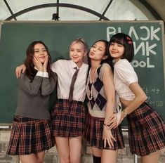 three girls are posing in front of a blackboard