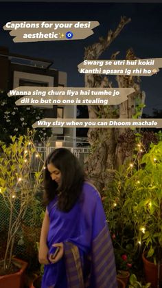 a woman in a blue sari standing next to potted plants