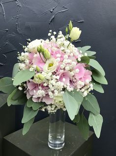 a vase filled with pink and white flowers sitting on top of a green table next to a black wall