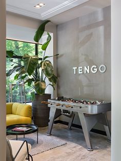 a living room with a foosball table in the center and a potted plant next to it