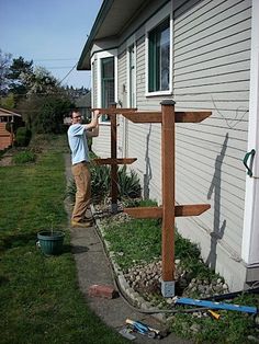 a man standing in front of a house next to a wooden cross