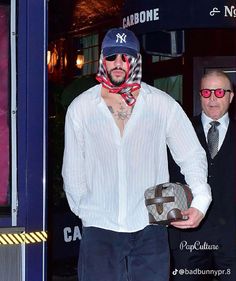 a man in a white shirt and red scarf is walking out of a blue door