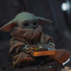 a baby yoda holding a bowl of food