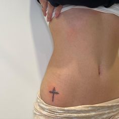 a woman with a cross tattoo on her lower back and the bottom part of her stomach