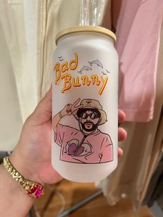 a person holding up a white can with an image of a man wearing sunglasses on it