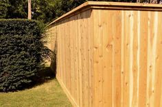 a tall wooden fence next to a lush green field