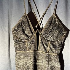 a bra that is hanging on a hanger in front of a white curtain with an intricate pattern