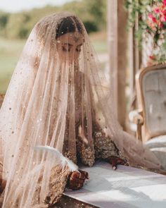 a woman wearing a veil sitting on top of a bench