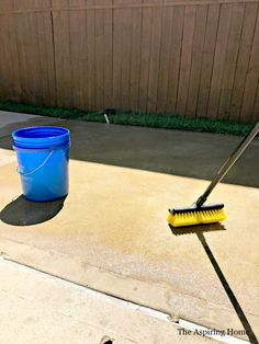 a bucket and brush sitting on the ground next to a blue bucket with a yellow handle