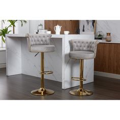 two gray and gold bar stools in front of a counter