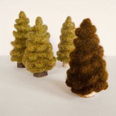 three needled trees in different colors on a white surface with one tree standing out from the others