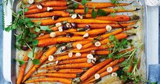 carrots with herbs and olives on a baking sheet