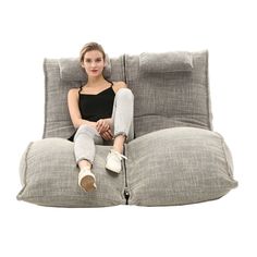 a woman sitting on top of a gray pillow