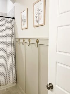 a white bathroom with two pictures on the wall and a shower curtain in the corner