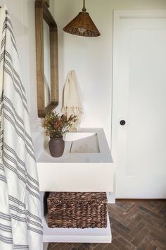 a white sink sitting under a bathroom mirror next to a wooden cabinet and towel rack