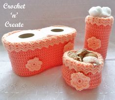 two crocheted toilet paper holders with shells in the center and flowers on them