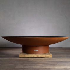 a large metal bowl sitting on top of a wooden table next to a gray wall