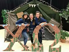 three girls standing in front of a tent with the word yes spelled out on it