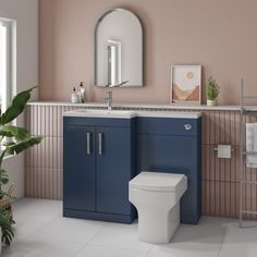 a white toilet sitting next to a blue sink in a bathroom with pink walls and tile flooring