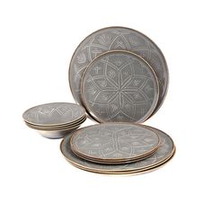 a set of four grey and gold dinnerware with an intricate design on the side