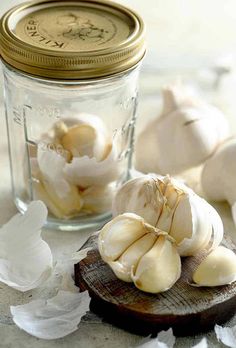 garlic cloves are sitting on a cutting board next to a jar