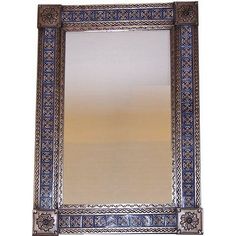 an ornate mirror with blue and white designs on the edges, hanging from a wall