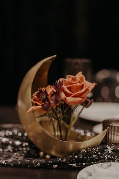 a vase with flowers sitting on top of a table next to a crescent shaped object