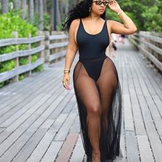 a woman in a black bodysuit walking on a boardwalk