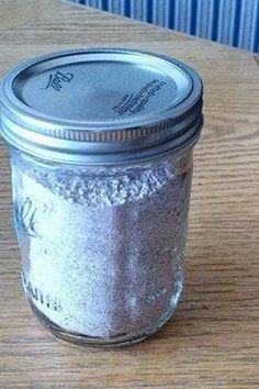 a glass jar filled with silver glitter sitting on top of a wooden table