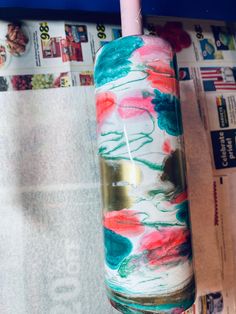 a pink and blue vase sitting on top of a newspaper