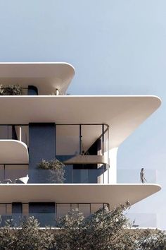 a tall building with balconies on top of it's sides and trees in the foreground