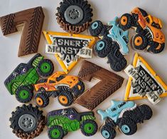 decorated cookies are arranged in the shape of monster trucks and tractor tracks on a white surface