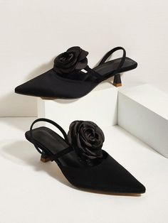 two pairs of black high heeled shoes with a rose on the toe and side