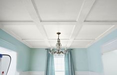 a chandelier hanging from the ceiling in a room with blue walls and curtains