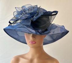 The featured hat is a navy blue organza hat with a dramatic design. The design has a soft  bunch of organza petals in navy blue atop a very large crinoline bow with satin edges.   This  one of a kind hat by Letty is very stylish and chic. This special hat has an Audrey Hepburn style look to it. This hat will be perfect for Church  or  for the Kentucky Derby ,Tea Party, Wedding Party, Easter hat, Downton Abby hat and any other special  occasion. Brim: 4" Rise: 3.5" Size:  22" Fitted Navy Hat For Kentucky Derby, Elegant Navy Wide Brim Hat, Elegant Navy Hats With Curved Brim, Elegant Navy Hat For Evening, Navy Hat For Kentucky Derby Party, Navy Party Hat For Kentucky Derby, Audrey Hepburn Hat, Hat Tea Party, Easter Hat