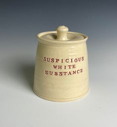 a ceramic container with the words suspicious white substance on it's lid and red lettering