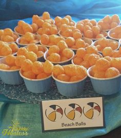 there are many small plastic cups filled with oranges on the table at this beach ball party