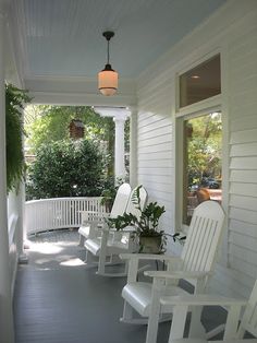 two white rocking chairs sitting on the front porch