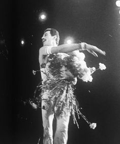 an old photo of a man on stage with flowers in his hand and lights behind him