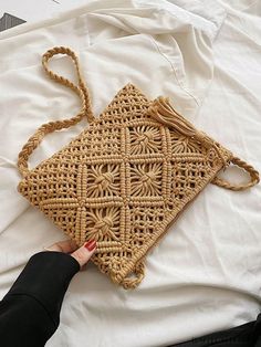 a woman is holding a woven purse on top of a white sheet with her hand