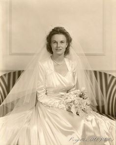 an old black and white photo of a woman in a wedding dress sitting on a couch