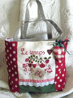 a red and white polka dot bag with a strawberry on the front, sitting on top of a blanket