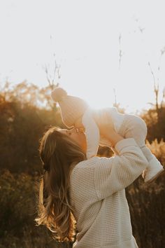 a woman holding a baby up in the air