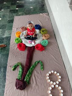 a small child sitting on top of a blanket next to some beads and other items