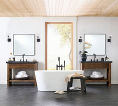 a white bath tub sitting under two mirrors