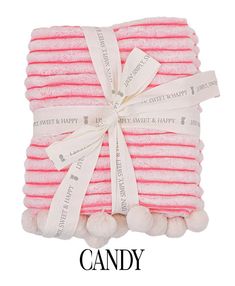 four pink and white towels wrapped in ribbon with pom - poms on top