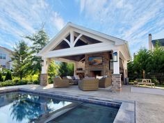 an outdoor living area next to a swimming pool and covered patio with seating around the fire place