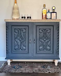 an ornate cabinet with wine glasses and liquor bottles on top is shown in this image